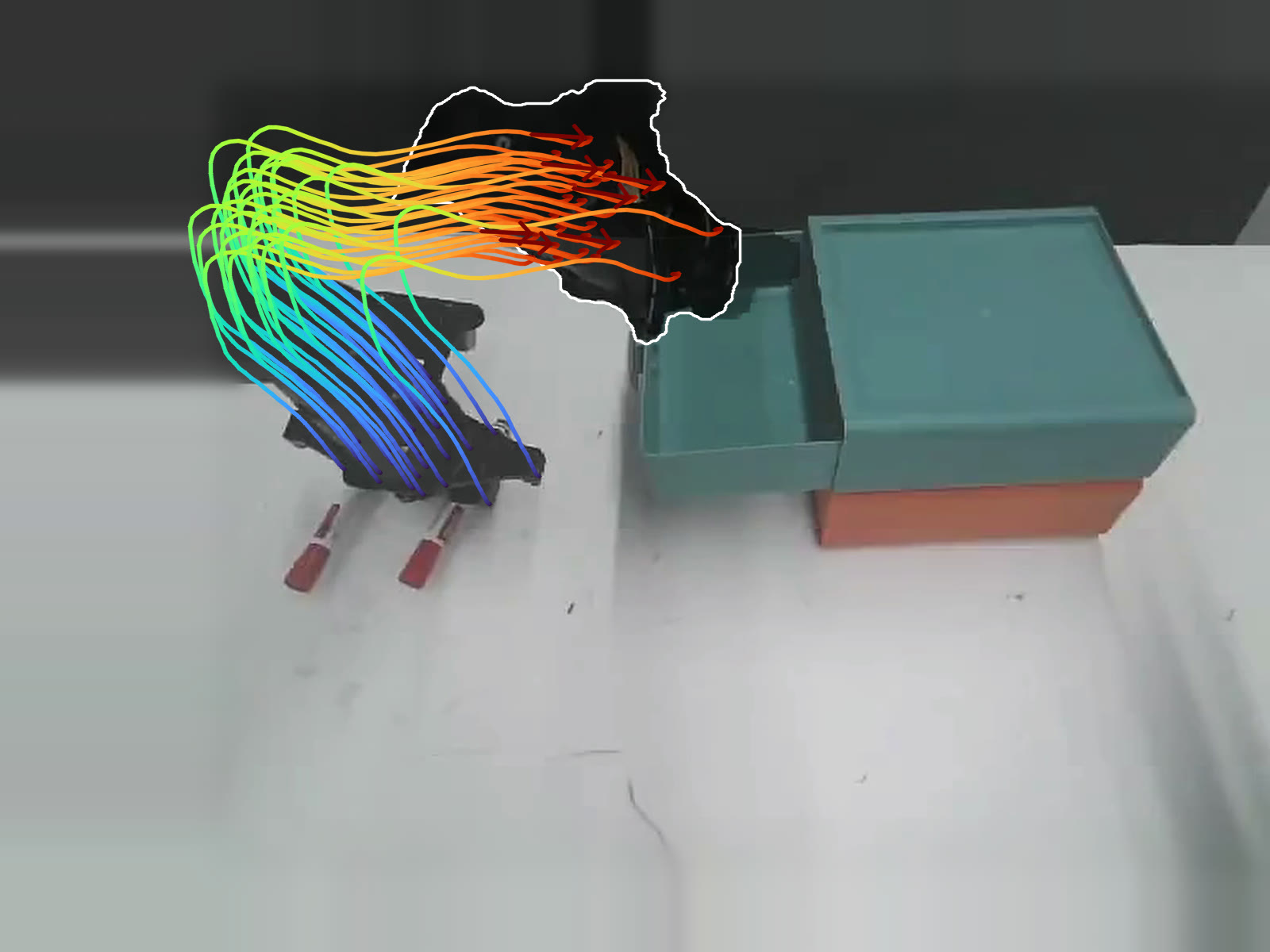 Scene flow trajectories drawn over a robot gripper moving above two pens next to an open drawer